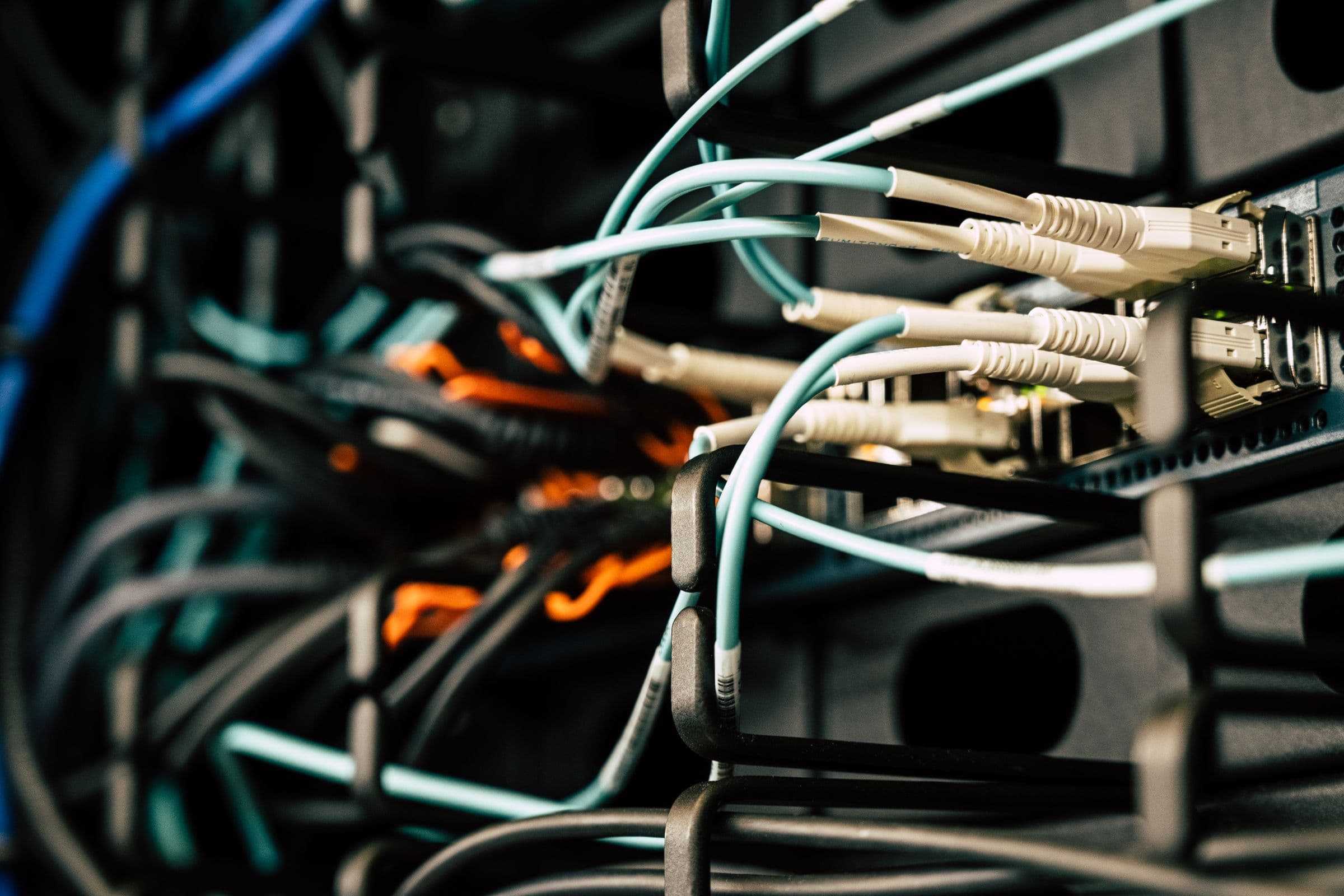 Netwerkkabels in een serverkast, in donker licht met een oranje accent