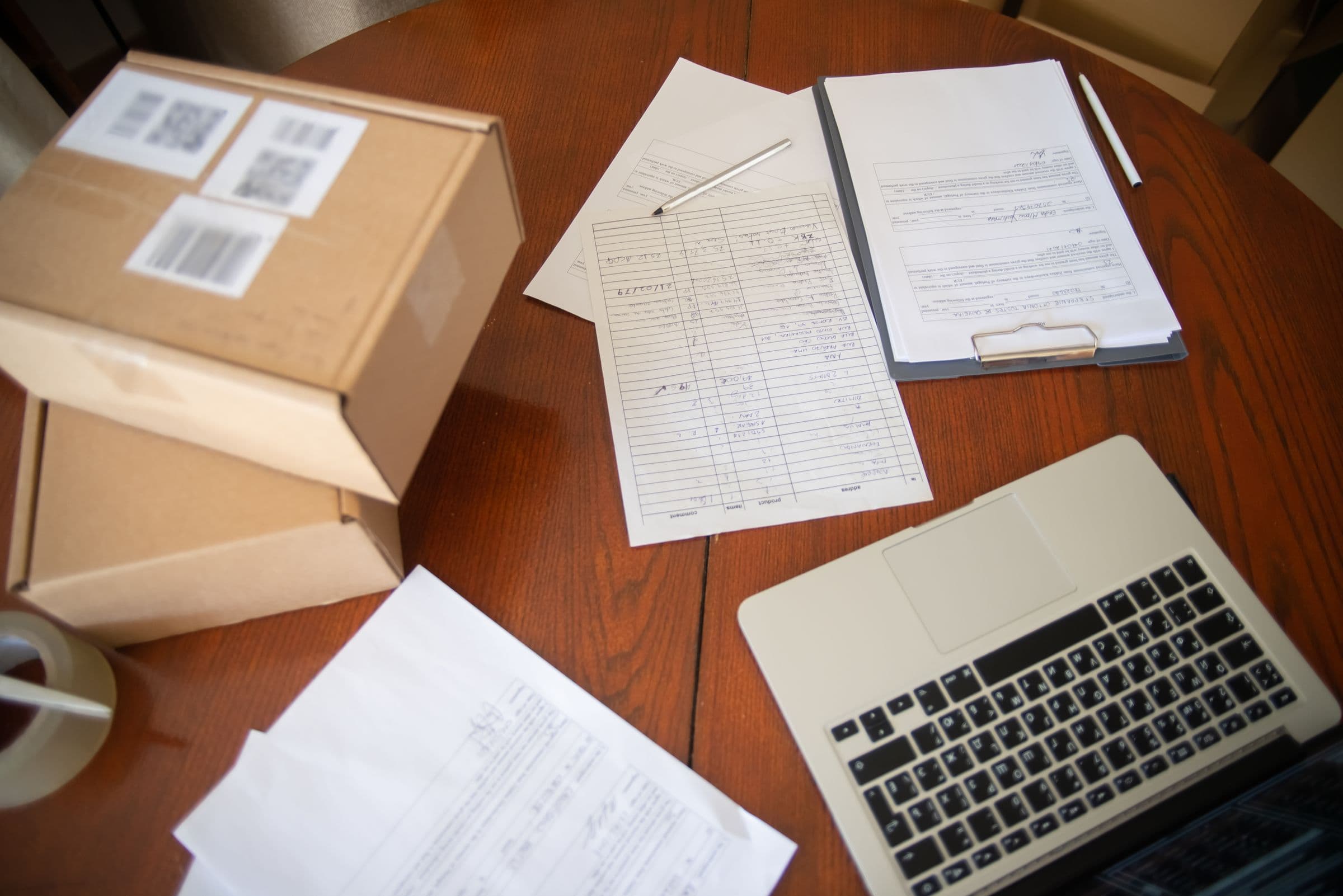 Kartonnen dozen, papieren bestelformulieren en een laptop op een houten tafel