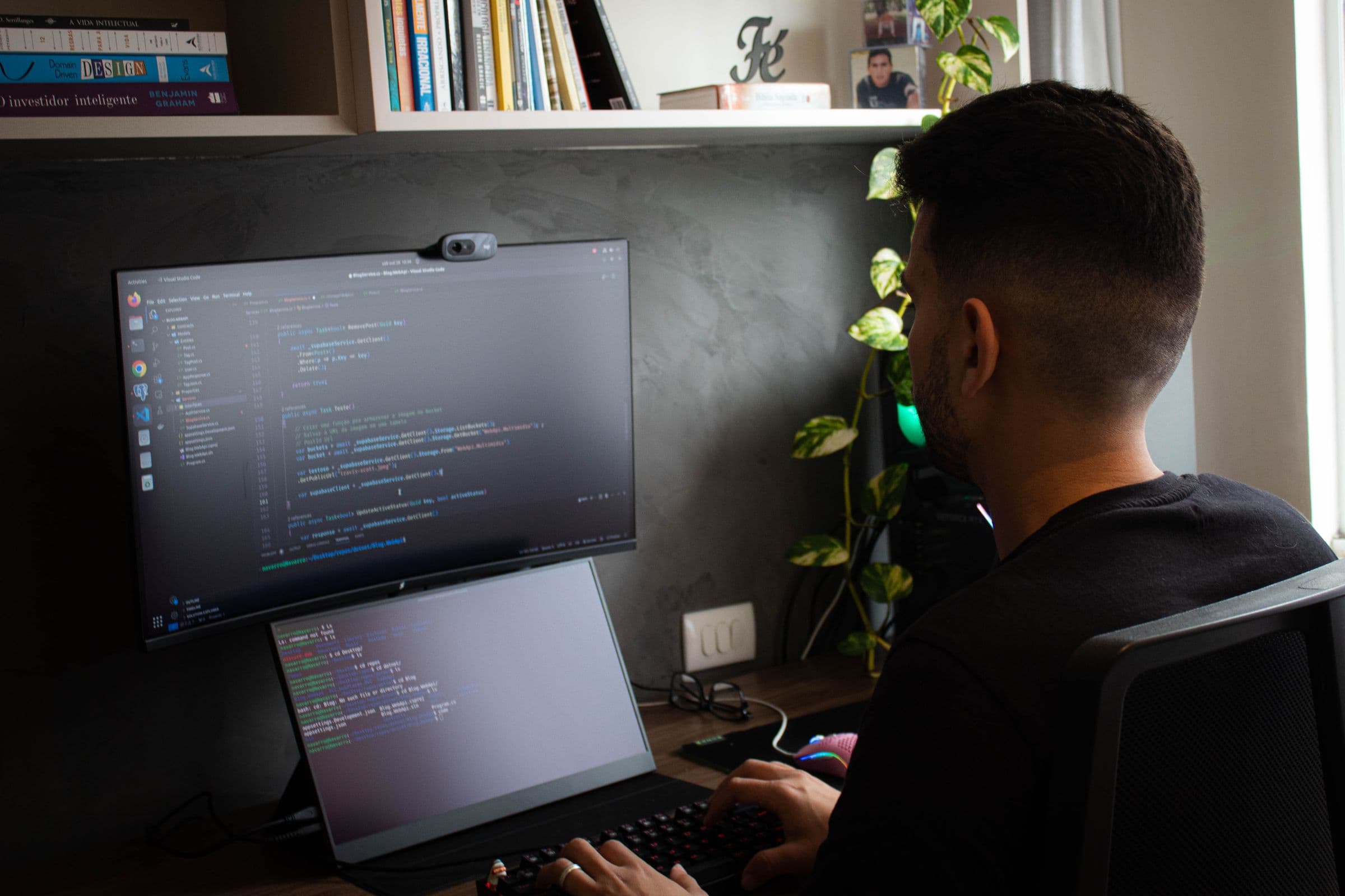 Ontwikkelaar van achteren aan een bureau met twee schermen vol code
